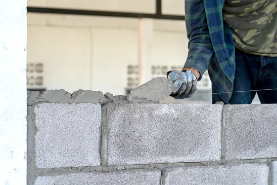 Intérieur en cours de rénovation, artisan carreleur installant du carrelage imitation bois sur chape béton