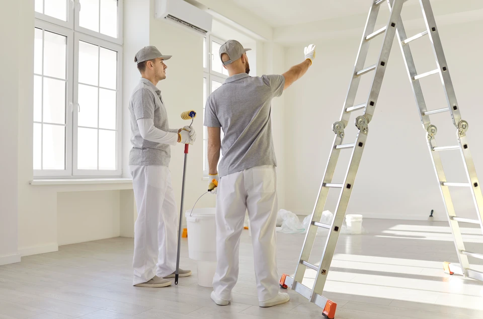 Scène intérieure d'atelier avec deux personnes effectuant des travaux de peinture